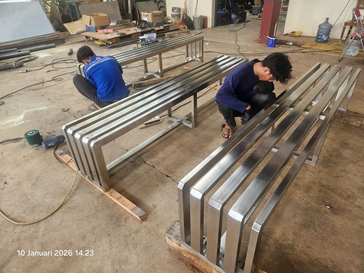 Dua pekerja merakit rangka bangku stainless steel di workshop