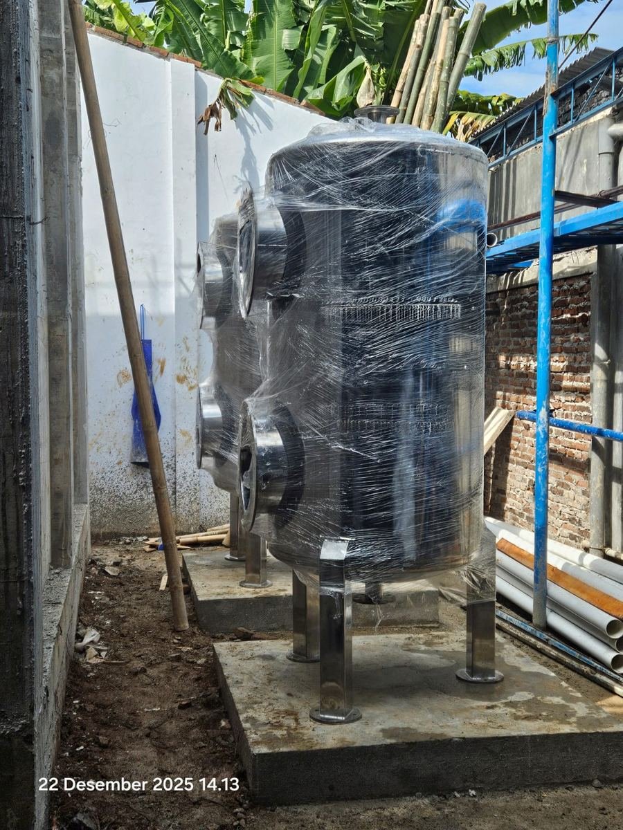 Tangki stainless steel yang sudah terpasang di lokasi dengan dudukan beton
